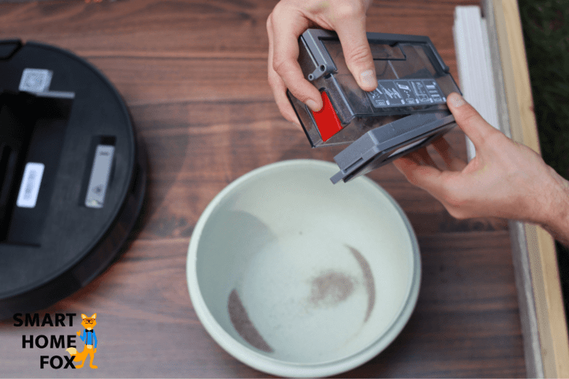 Der mobile Staubbehälter des Ecovacs Deebot OZMO 950 wird über dem Mülleimer ausgeleert